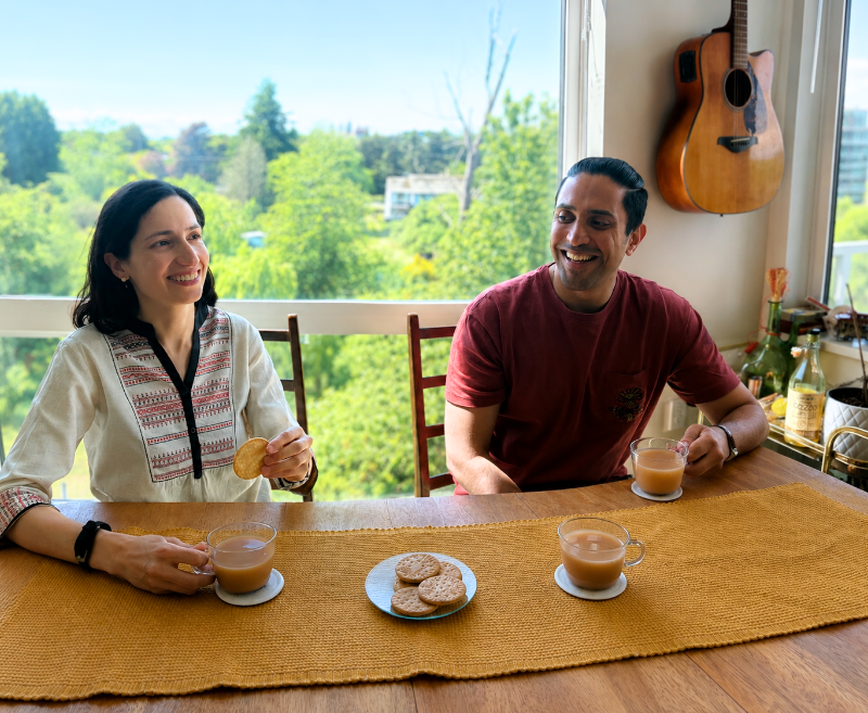 The founders of Nosh kosh sharing a moment over cups of authentic Masala Chai and biscuits on a sunny balcony.