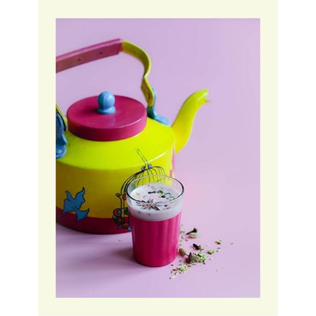Colorful teapot with a glass of milk and cookies on a pink background